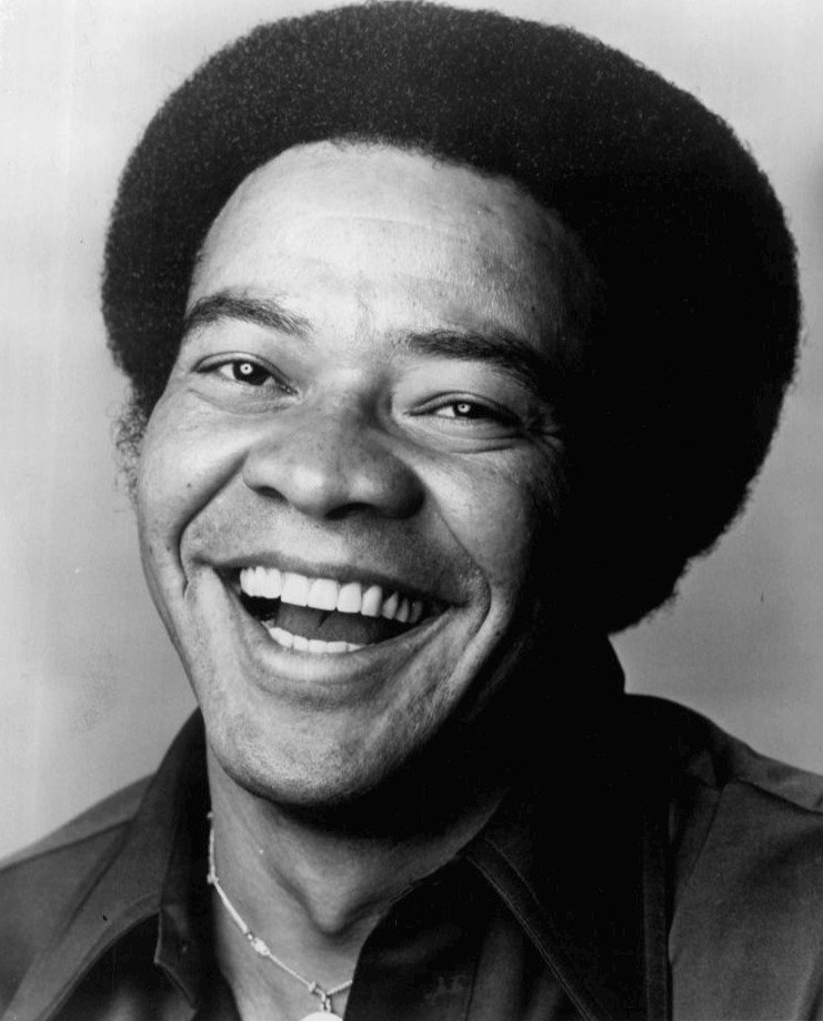 Black-and-white portrait of Bill Withers, smiling.