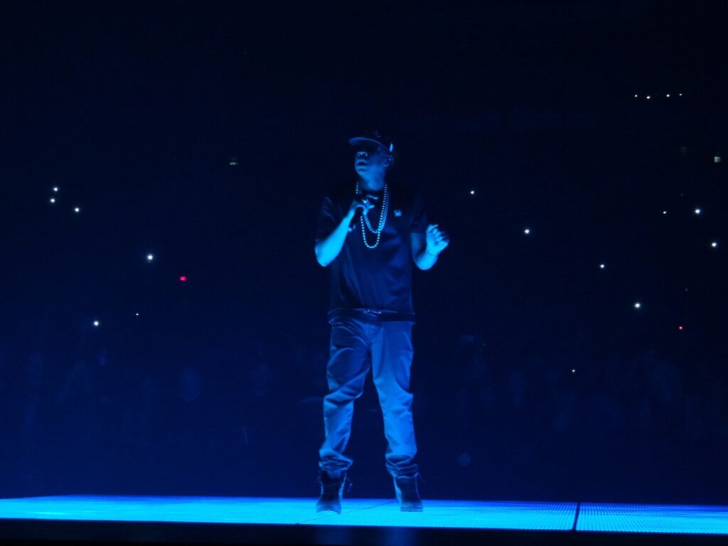 Jay-Z performs onstage under blue lighting.